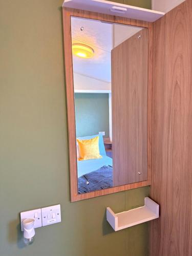 a mirror on a wall with a bed in a room at The Eden - Sleeps 8 Pet Friendly Free Wi-Fi With Patio & Hub Passes Camber Sands Cosy Spacious Modern 8 Berth Caravan in Camber