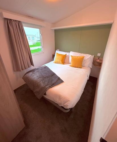 a bedroom with a large bed with yellow pillows at The Eden - Sleeps 8 Pet Friendly Free Wi-Fi With Patio & Hub Passes Camber Sands Cosy Spacious Modern 8 Berth Caravan in Camber