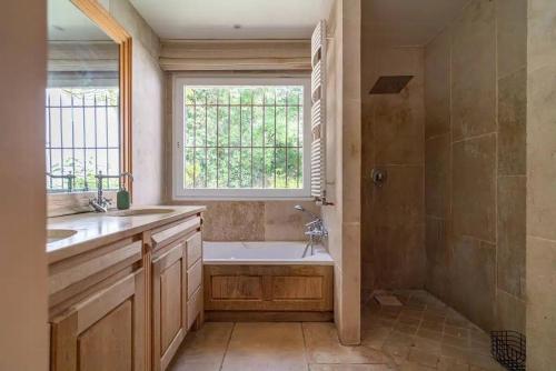 ein Badezimmer mit Badewanne und Waschbecken und einem Fenster in der Unterkunft Provencal Villa With Pool In Montferrier-Sur-Lez in Montferrier-sur-Lez