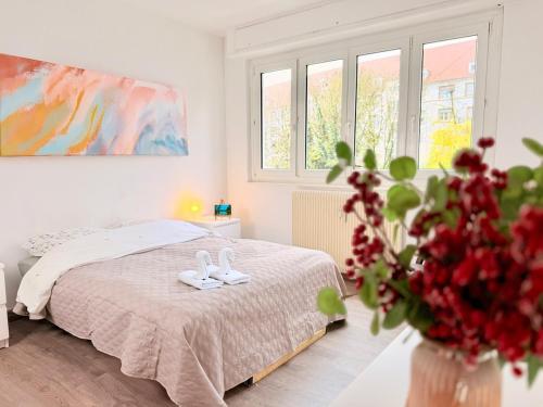 a white bedroom with a bed and a vase of flowers at Cocon du Quai - Proche marché de Noël in Strasbourg