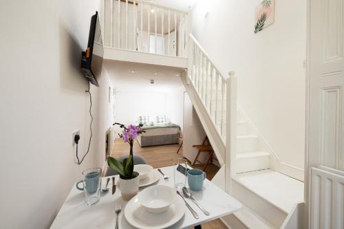 a white room with a table and a staircase at Charmstay Swiss Cottage in London