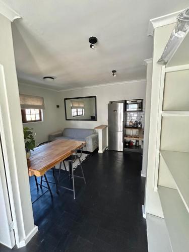 una cucina e una sala da pranzo con tavolo e frigorifero di De Kalkery Apartment a Kalk Bay