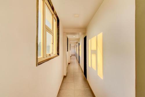 einen langen Flur mit weißen Wänden und Fenstern in der Unterkunft FabHotel World King in Pune