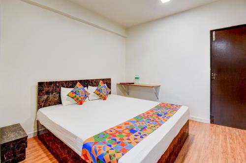 a bedroom with a large white bed with colorful pillows at FabHotel World King in Pune