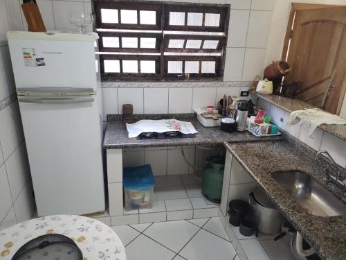une petite cuisine avec un réfrigérateur et un évier dans l'établissement Casa de praia, à Mongaguá