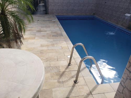 une piscine bleue avec une table et une table et une table dans l'établissement Casa de praia, à Mongaguá