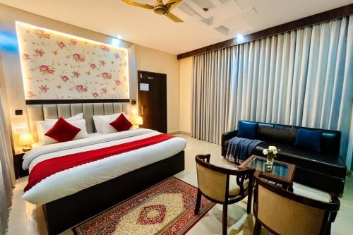 Un dormitorio con una cama, un sofá y una mesa. en Hotel Ramawati Classic, A Luxury Hotel & Resort, Haridwar, en Haridwar