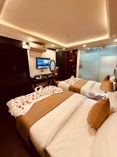 a hotel room with two beds and a television at Majestik Hanoi Hotel in Hanoi