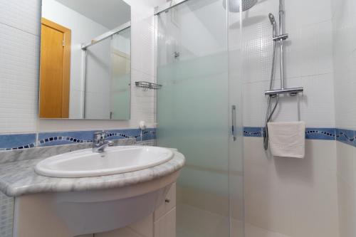 ein Badezimmer mit Waschbecken und Glasdusche in der Unterkunft Global Properties, Piso practico, con terraza y piscina en la playa de Canet in Canet d'en Berenguer