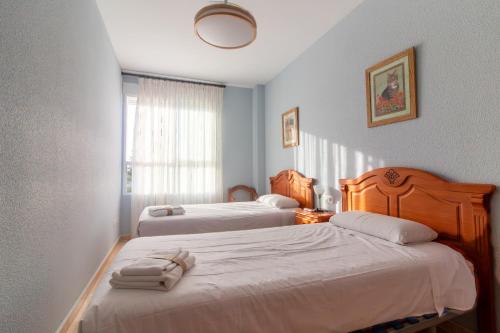 ein Hotelzimmer mit zwei Betten und einem Fenster in der Unterkunft Global Properties, Piso practico, con terraza y piscina en la playa de Canet in Canet d'en Berenguer