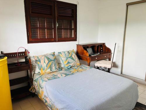 a bedroom with a bed and a piano at Chambre d'Hôtes Créole Bas du Fort in Le Gosier