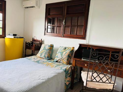 ein Schlafzimmer mit einem Bett und einem Schreibtisch mit einem Radio in der Unterkunft Chambre d'Hôtes Créole Bas du Fort in Le Gosier