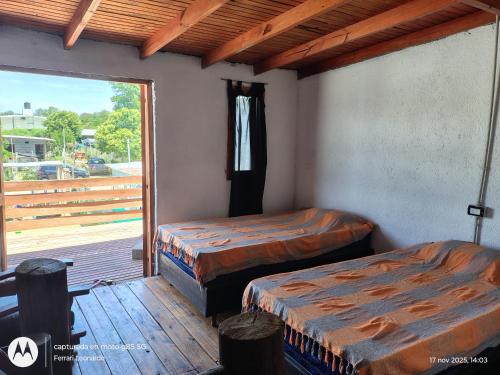 two beds in a room with a balcony at Cabaña Anisacate in Villa Anizacate