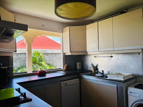 eine Küche mit Spüle und Fenster in der Unterkunft Chambre d'Hôtes Créole Bas du Fort in Le Gosier