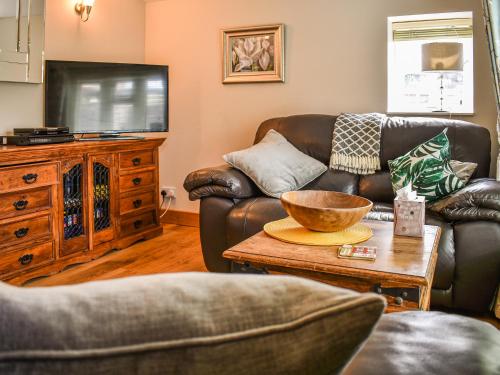 ein Wohnzimmer mit zwei Sofas und einem Fernseher in der Unterkunft May Cottage in Rendham