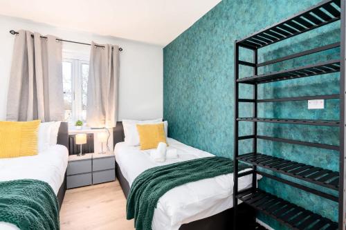 two beds in a small room with green walls at Spacious 3 Bedroom Home with 6 Beds Private Garden and Driveway Parking in Manor