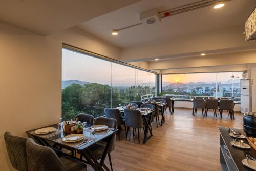 a restaurant with tables and chairs and a large window at The Classic Crown Udaipur - A Luxury Hotel by Lake Pichola in Jāmb