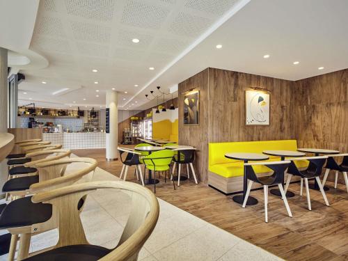 un restaurant avec des tables et des chaises dans une cafétéria dans l'établissement Mercure Paris la Défense Grande Arche, à Nanterre