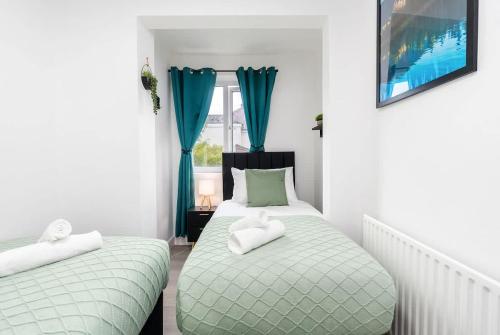 two beds in a small room with blue curtains at Spacious 4 Bedroom House with 8 Beds and Private Driveway Parking in Heeley