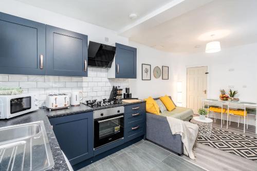 a kitchen with blue cabinets and a living room at 4 Bedroom House with 2 Bathrooms - Back Garden with Outdoor Seating Sleeps 7 in Heeley