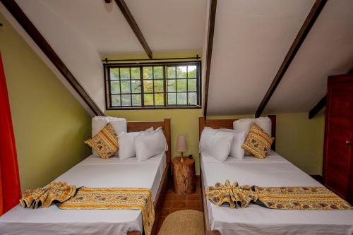 two beds in a small room with a window at Amani Farmhouse in Usa River