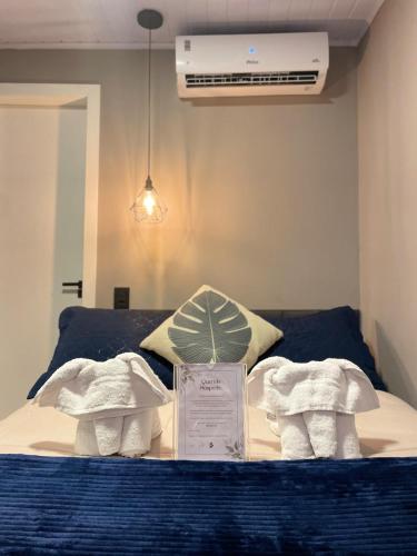 ein Bett mit zwei Handtüchern und einer Plakette darauf in der Unterkunft Pousada Aurora - Com Lindo Jardim em Termas do Gravatal in Gravatal