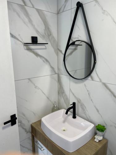 ein Badezimmer mit einem weißen Waschbecken und einem Spiegel in der Unterkunft Pousada Aurora - Com Lindo Jardim em Termas do Gravatal in Gravatal