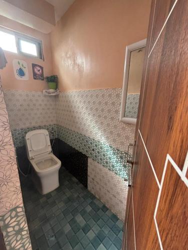 a bathroom with a toilet and a tiled floor at V V Homestay in Darjeeling