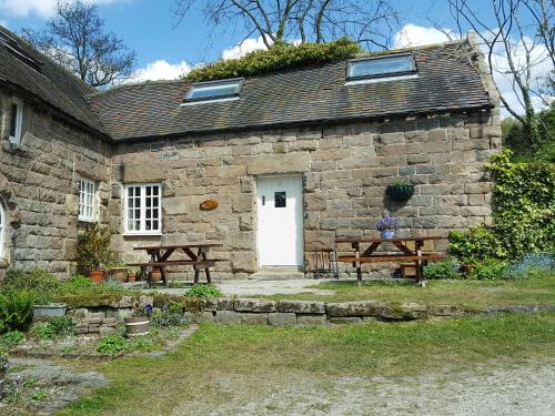 a stone house with two benches and a white door at Nightingale Cottage - Ukc1570 in Crich