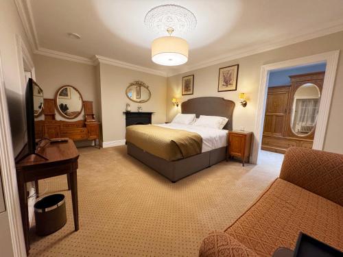 ein Schlafzimmer mit einem Bett und einer Couch und einem Fernseher in der Unterkunft Cashel Regency Townhouse in Cashel