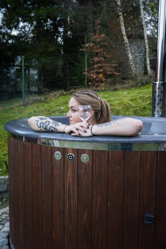 a woman in a hot tub with a glass of wine at Domek za Księżycem - azyl z balią, kominkiem i prywatnym ogrodem, Ustroń in Ustroń