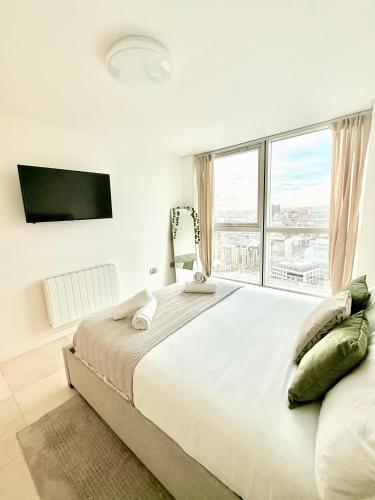 a white bedroom with a large bed and a large window at 22nd Floor Luxury City Centre Apartment in Belfast