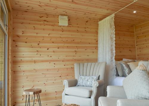 Cette chambre est dotée d'un mur en bois, d'un canapé et d'une chaise. dans l'établissement Fine Country Stays, à Bubwith