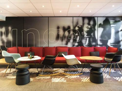 - un hall avec un canapé rouge, des tables et des chaises dans l'établissement ibis Paris Saint-Denis Stade Sud, à Saint-Denis