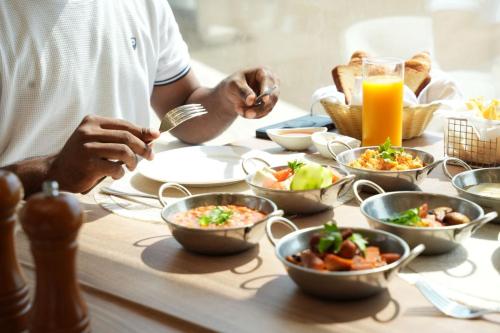 een persoon die aan een tafel zit met schalen vol eten bij Dana Beach Resort in Al Sharqiyah