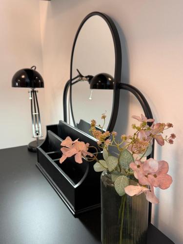 a mirror and a vase with flowers on a table at Bylinkový Apartmán in Banská Bystrica