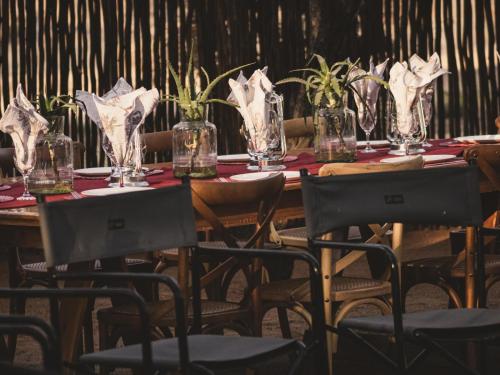 ein langer Holztisch mit Stühlen und Gläsern darauf in der Unterkunft Tshikwalo Guest House in Klipdrift