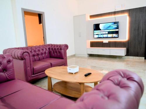 ein Wohnzimmer mit lila Möbeln und einem Fernseher in der Unterkunft Amaira Studio living - Coimbatore in Coimbatore