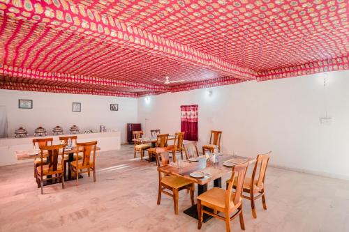 une salle à manger avec tables et chaises sous un plafond rouge dans l'établissement Desert Yatra Resort, à Sām