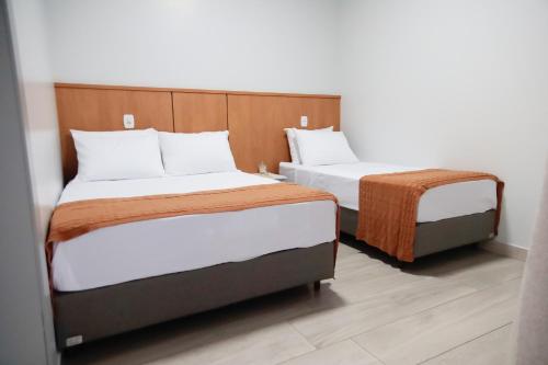two beds sitting next to each other in a room at Pousada Encantos de Itá in Itá
