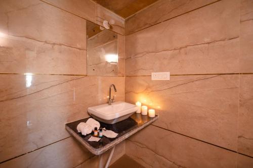 La salle de bains est pourvue d'un lavabo et d'un mur en pierre. dans l'établissement Desert Yatra Resort, à Sām