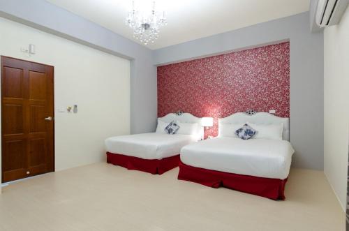 two beds in a room with a red wall at Love Love Taitung in Taitung City