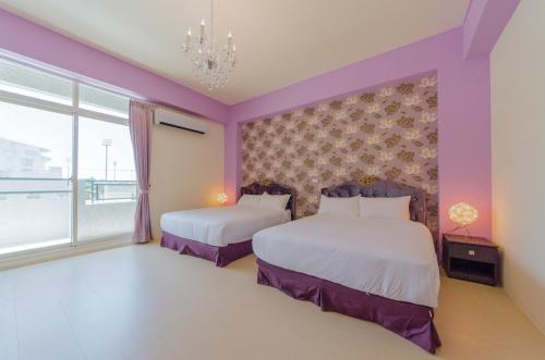 two beds in a room with purple walls and a window at Love Love Taitung in Taitung City