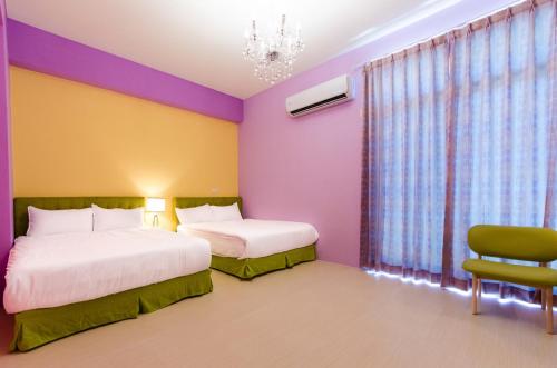 a colorful bedroom with two beds and a chair at Love Love Taitung in Taitung City