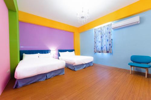 a colorful bedroom with two beds and a chair at Love Love Taitung in Taitung City