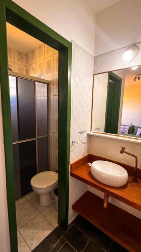 ein Badezimmer mit Toilette, Waschbecken und Spiegel in der Unterkunft Pousada in Bombinhas