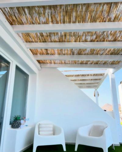 a room with two white chairs and a thatched ceiling at Estudio Garzolini in San José
