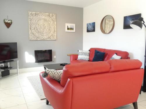 a living room with a red couch and a tv at Railway Cuttings in Falstone
