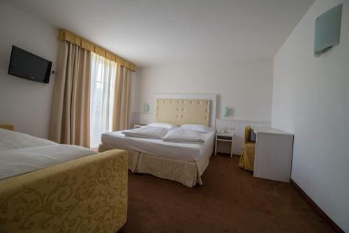 a hotel room with two beds and a television at Alpen Hotel Eghel in Folgaria