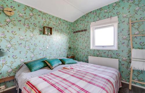 ein Schlafzimmer mit einem Bett mit grüner Blumentapete in der Unterkunft Strandhuis `Meerzicht` in Lauwersoog